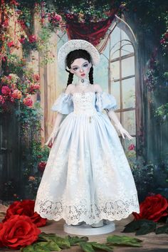 a doll dressed in white is standing next to roses