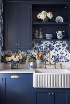 a kitchen with blue cabinets and floral wallpaper on the backsplash is shown