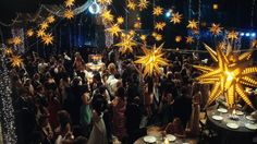 a large group of people standing around each other in front of a stage with stars on it