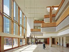 an empty lobby with lots of windows and people walking in the hallway on either side