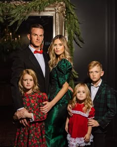 a man and two children standing next to each other in front of a christmas tree