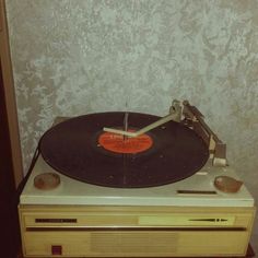 an old record player sitting on top of a wooden table next to a white wall