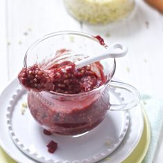 a glass jar filled with raspberry sauce on top of a white plate