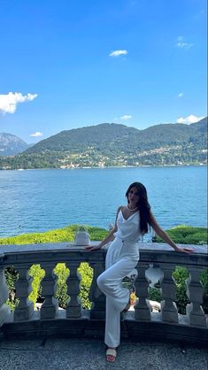 a woman is posing on a balcony near the water