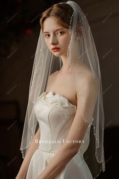 a woman wearing a wedding veil with pearls on it