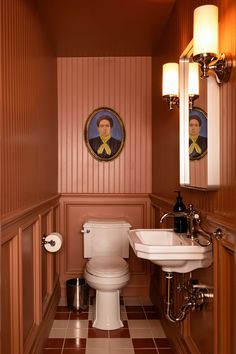 a bathroom with a toilet, sink and pictures on the wall in it's corner