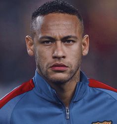 a close up of a soccer player wearing a blue and red jacket with tattoos on his face