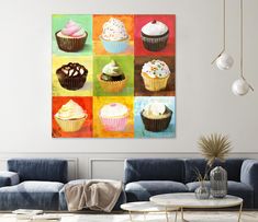 a living room with blue couches and paintings on the wall above them, including cupcakes