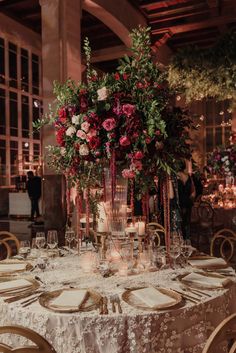 the table is set with candles and flowers in tall glass vases on each side