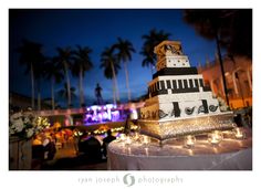 a wedding cake sitting on top of a table with lit candles in front of it