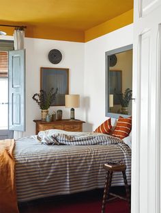 a bed sitting in a bedroom next to a dresser and mirror on top of a wall