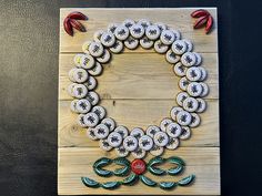 a wreath made out of buttons sitting on top of a wooden board next to a black wall