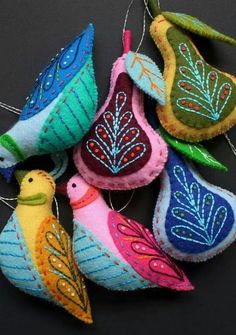 several colorful ornaments hanging from strings on a black surface with one bird ornament in the middle