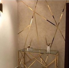 a glass table sitting in front of a wall with gold trimmings on it