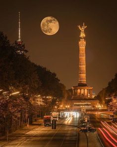 a full moon is seen above the monument in this nighttime scene with cars passing by