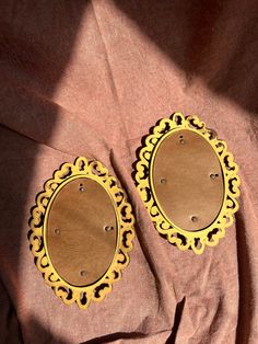 two circular wooden plaques sitting on top of a pink cloth covered table next to each other