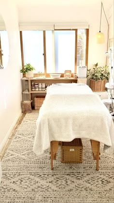 a bed with a white blanket on top of it in a room next to a window