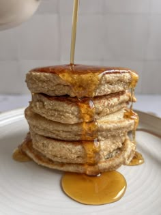 a stack of pancakes with syrup being drizzled on top