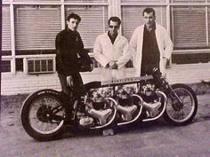 three men are standing next to a motorcycle