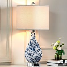 a blue and white vase sitting on top of a table next to a lamp