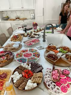 a table filled with lots of food on top of a white kitchen counter next to a sink