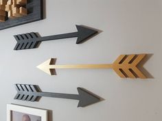 three metal arrows are mounted on the wall next to two framed photos and a wooden frame