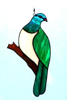 a stained glass bird sitting on top of a tree branch in front of a blue sky