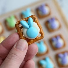 a hand holding a tiny pretzel with blue and white frosting on it