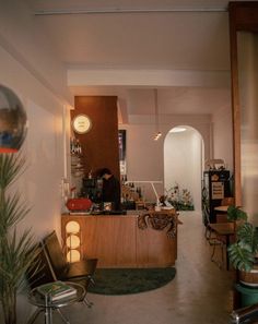 the interior of a restaurant with plants in pots on the counter and an open door leading to another room