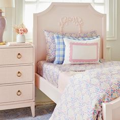 a bedroom with pink bedding and white dresser next to the window in front of it