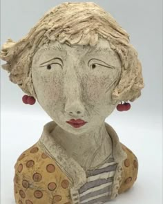 a ceramic sculpture of a woman's head with red earrings on her ears and hair