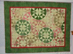 a green and red quilt hanging on the wall