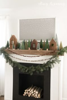 a fireplace decorated for christmas with pine trees and houses on the mantel above it