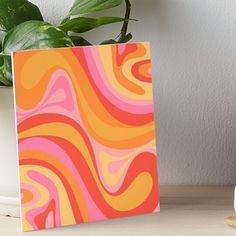 an orange, pink and yellow swirl pattern art board print on wood by the wall