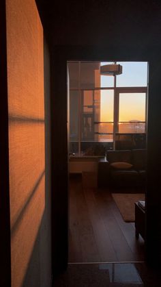 an open door leading to a living room with a view of the city outside at sunset