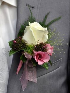 a man in a gray suit holding a pink and white rose boutonniere