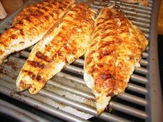 three fish fillets are cooking on a grill