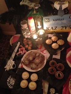 a table topped with cupcakes and desserts next to a bottle of alcohol