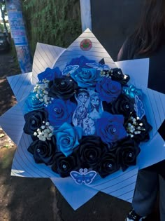 a bouquet of blue and black roses on top of white paper in front of a woman's face