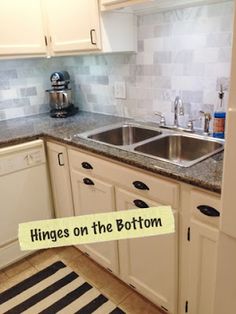 a kitchen with white cabinets and black and white striped rug on the floor next to the sink