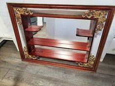 an old wooden shelf with two benches in the middle and a mirror on the wall behind it