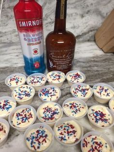 cupcakes with white frosting and sprinkles next to a bottle of liquor