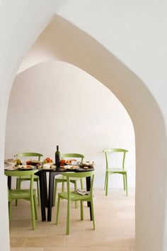 a table with four chairs and a bottle of wine on it in an archway between two walls