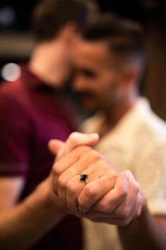 two men are standing close to each other and one is holding his hand out for the camera