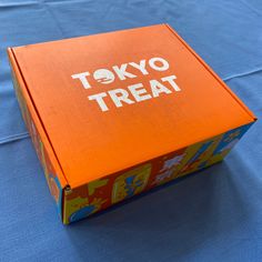 an orange box sitting on top of a blue cloth covered tablecloth that says tokyo treat