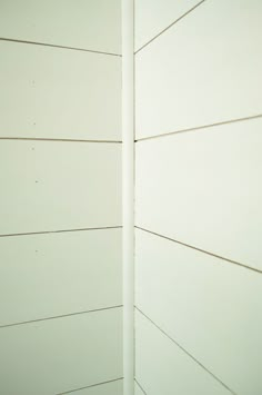 the corner of a white painted wall with vertical lines on it's sides and one line at the end