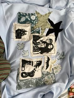 several different pieces of fabric on top of a blue cloth covered bed spread with white and black designs