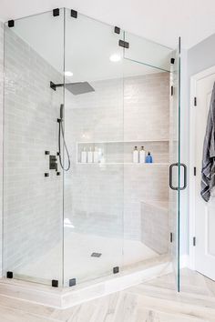 a bathroom with a walk in shower next to a white door and tiled walls on the wall