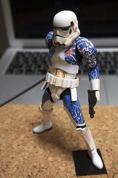 a star wars action figure is posed in front of a laptop