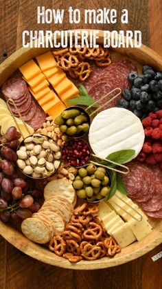 a wooden bowl filled with different types of cheeses and crackers next to grapes